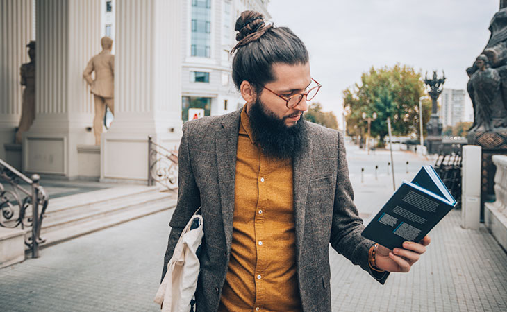 man in the street walking with a book
