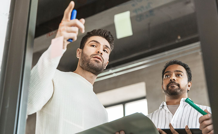 two men talking and taking notes