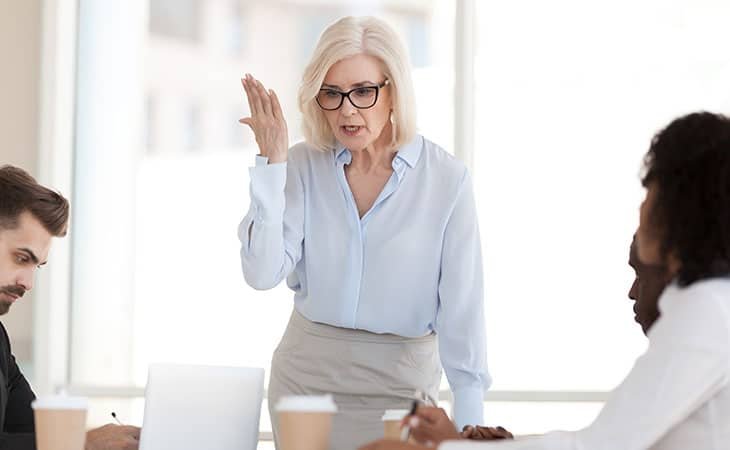 a woman with her hand up talking in an office