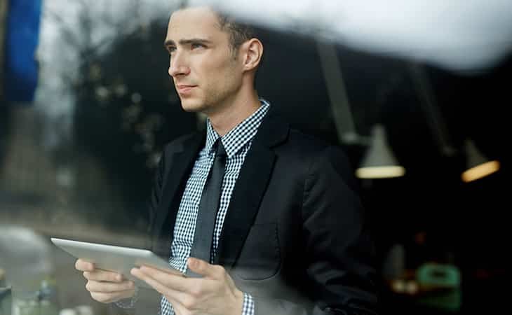 thoughtful-man-window-tablet